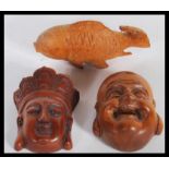 A group of three Japanese wooden hand carved netsukes to include a Meiji period Buddha head