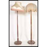 Two 20th Century Art Deco oak standard lamps with shades, both with turned uprights supported by a