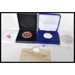 A group of three silver proof coins to include a 999 silver outbreak £20 coin, a ' For The