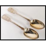 A pair of 19th Century Victorian silver hallmarked fiddle pattern table serving spoons, each spoon