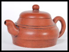 An early 20th Century Chinese Yixing teapot modelled in a brown clay with shaped handle and spout.