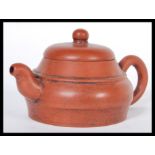 An early 20th Century Chinese Yixing teapot modelled in a brown clay with shaped handle and spout.