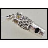 A stamped sterling silver whistle in the form of an owl having yellow and black glass eyes, bale