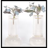 A pair of early 20th Century French hand worked enamel on metal floral flower sprays in glass column