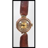 An early 20th Century Art Deco 9ct gold ladies wrist watch with a round face with a gilt dial,