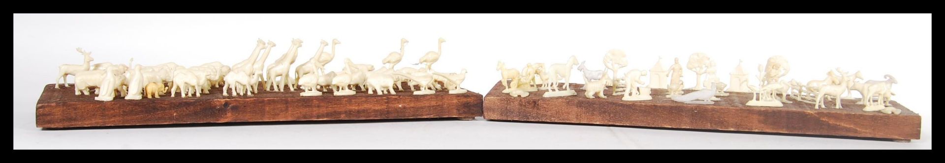 A selection of white faux ivory cast resin figures of animals mounted on a stained wooden base along