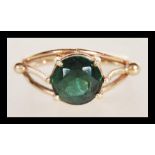A 9ct gold stamped ring having a large central prong set faceted green stone with gold ball finial