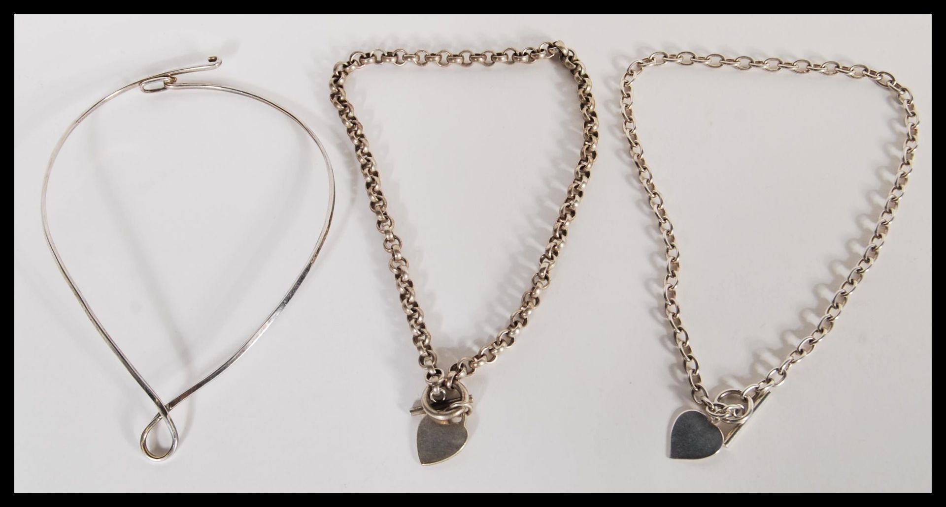 Three large sterling silver necklaces consisting of a rigid silver necklace with crossover end,