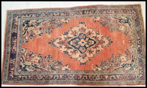 A 20th Century wool Persian floor carpet rug having a red ground central panel and geometric