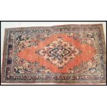 A 20th Century wool Persian floor carpet rug having a red ground central panel and geometric