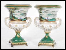 A pair of Continental German urn vases in the manner of Meissen raised on square bases with brass