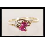 A hallmarked 9ct gold diamond and garnet stone ring having a prong set diamond with faceted red