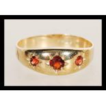 A hallmarked 9ct gold three stone garnet ring having three flush set faceted red stones. Weighs 2.