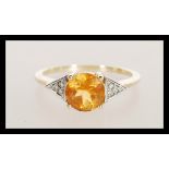 A hallmarked 9ct gold ladies ring set with a brilliant cut orange stone with triangular shoulders