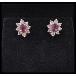 A pair of stamped 14k gold earrings set with oval cut rubies and diamond accent stones. Weight 2.6g.