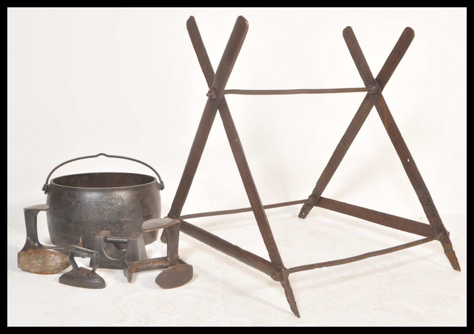A vintage early 20th Century cast iron saw horse base together with a cast iron cooking pot and