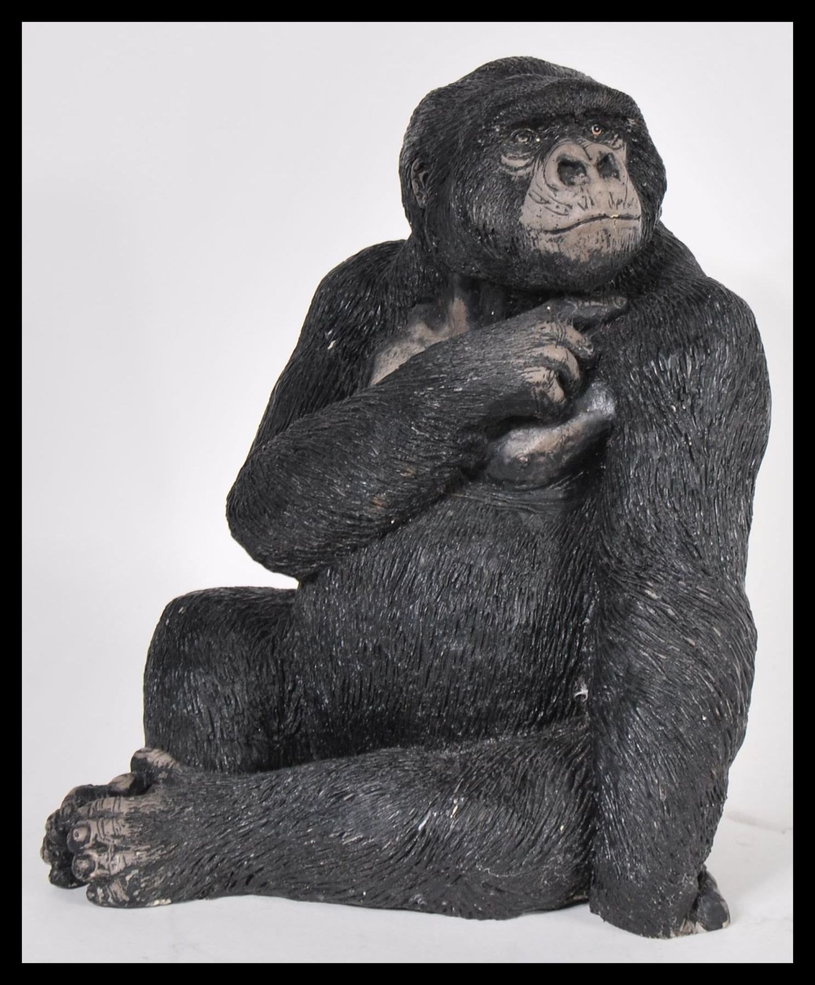 A 20th Century resin figurine in the form of a sitting gorilla, bearing the makers mark Carn to