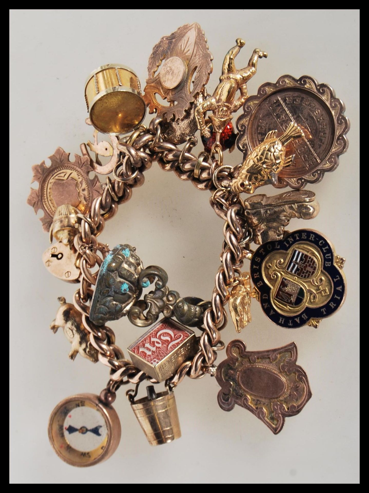 An early 20th Century stamped 9ct gold charm bracelet with a heart lock fastening, having a total of