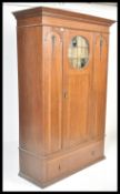 An early 20th Century Arts and Crafts movement solid oak single wardrobe armoire having a central