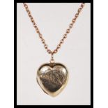 A 20th Century stamped 9ct gold heart locket having scrolled engraving to the front on an unmarked