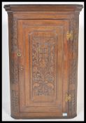 An 18th / 19th Century Georgian oak wall hanging corner cupboard, with later profuse carved
