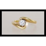 An unmarked but tests as 18ct gold and diamond having a brilliant cut diamond in a crossover