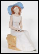 A 20th Ceramic figurine in the manner of Lladro by Nadal, the figurine modelled as a seated young