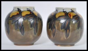 A pair of early 20th Century Royal Doulton ceramic vases of globular form having hand painted