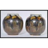 A pair of early 20th Century Royal Doulton ceramic vases of globular form having hand painted