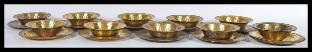 A group of twelve 20th Century Indian / Persian gilt brass bowls and saucers, each with geometric