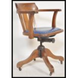 A vintage early 20th century Industrial oak office chair raised on a quadruped swivel base having