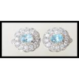 A pair of ladies silver dress earrings prong set with oval cut blue topaz stones with a halo of cz's