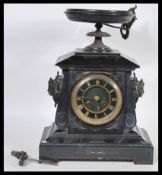 A late 19th century black slate cased mantel clock, of architectural form, the whole surmounted by