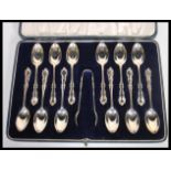 A set of 12 early 20th Century silver hallmarked tea spoons and a set of sugar tongs set within a