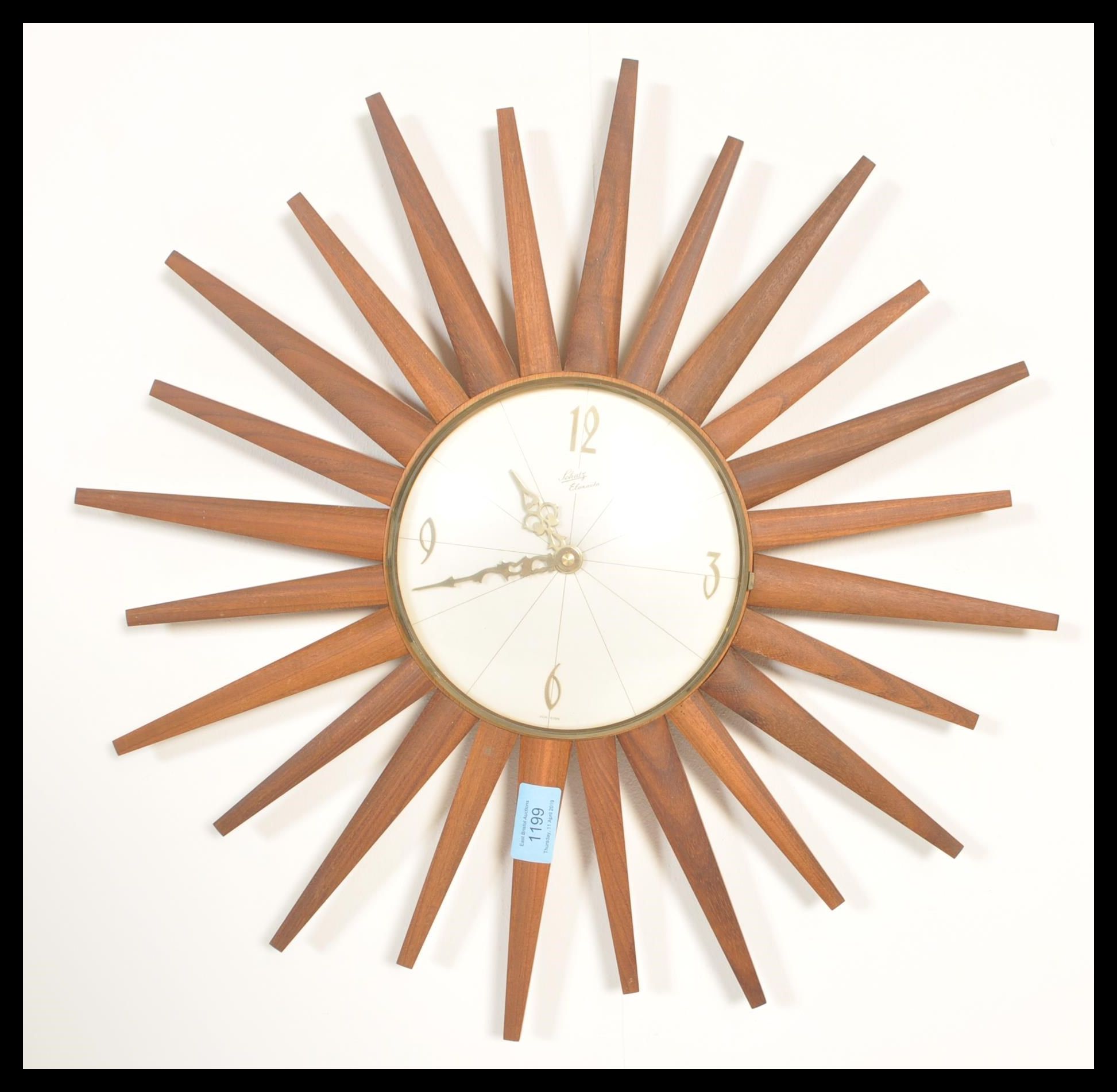 A retro 20th teak wood sunburst wall clock, the silvered clock face with baton numerals and marked