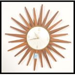 A retro 20th teak wood sunburst wall clock, the silvered clock face with baton numerals and marked