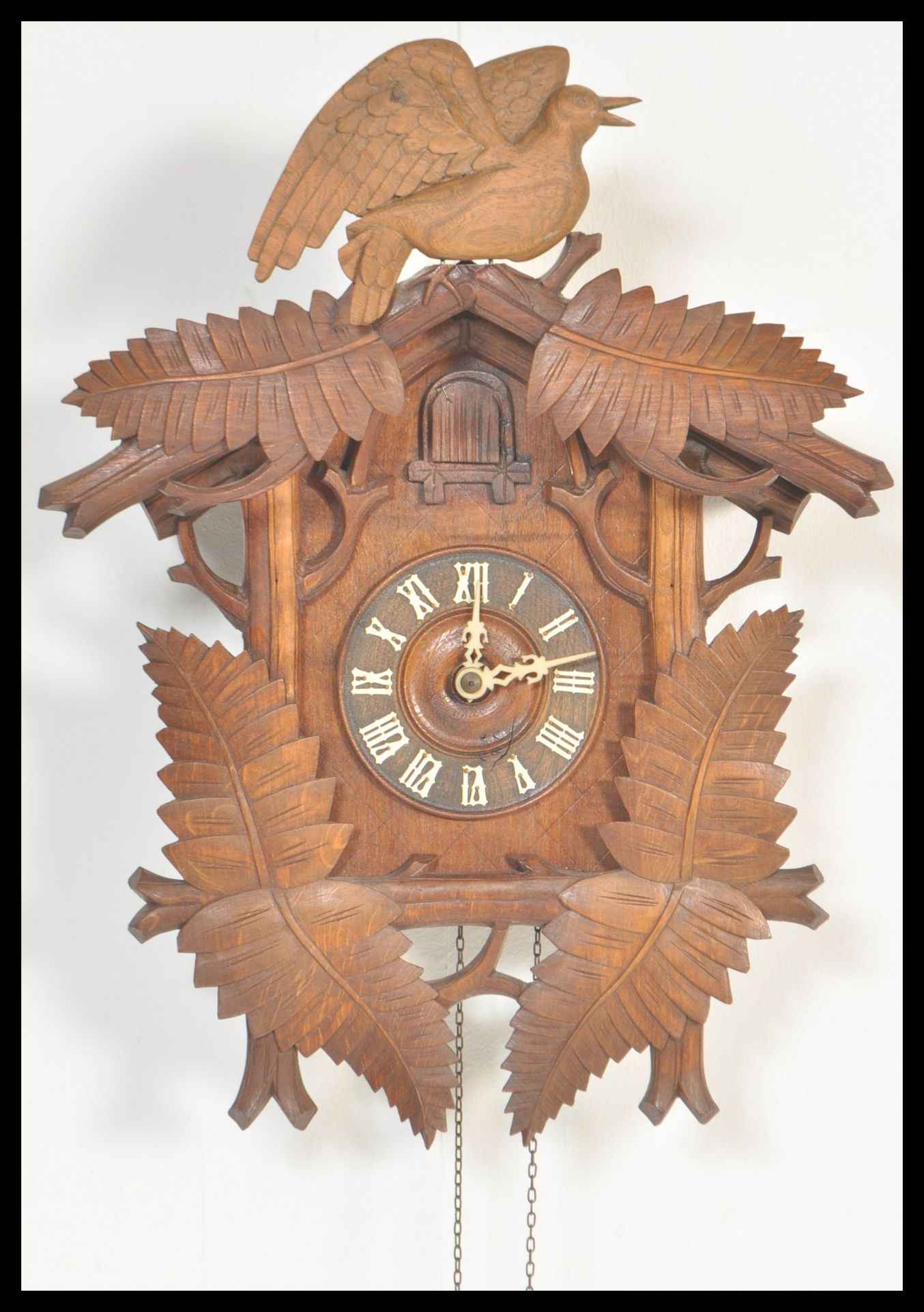 A 20th Century carved black forest cuckoo wall clock having two weights having roman numerals to the