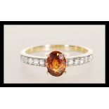 A hallmarked 9ct gold ring prong set with an oval cut brown having white accent stones to the