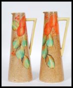 A pair of early 20th Century Art Deco jugs of tapering geometric form having hand painted autumn