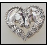 A stamped 925 silver heart brooch in the form of two horses having red stone eyes. Weight 19.1g.