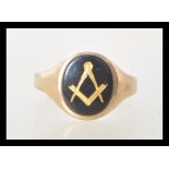 A hallmarked 9ct gold ring set with a oval onyx panel with a gilt masons symbol. Hallmarked London