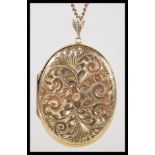 A hallmarked 9ct gold large locket pendant of oval form set to a 9ct gold curb link chain. Chased