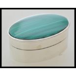 A silver pill / trinket box of oval form having a green malachite set lid. Weight 26.0g.