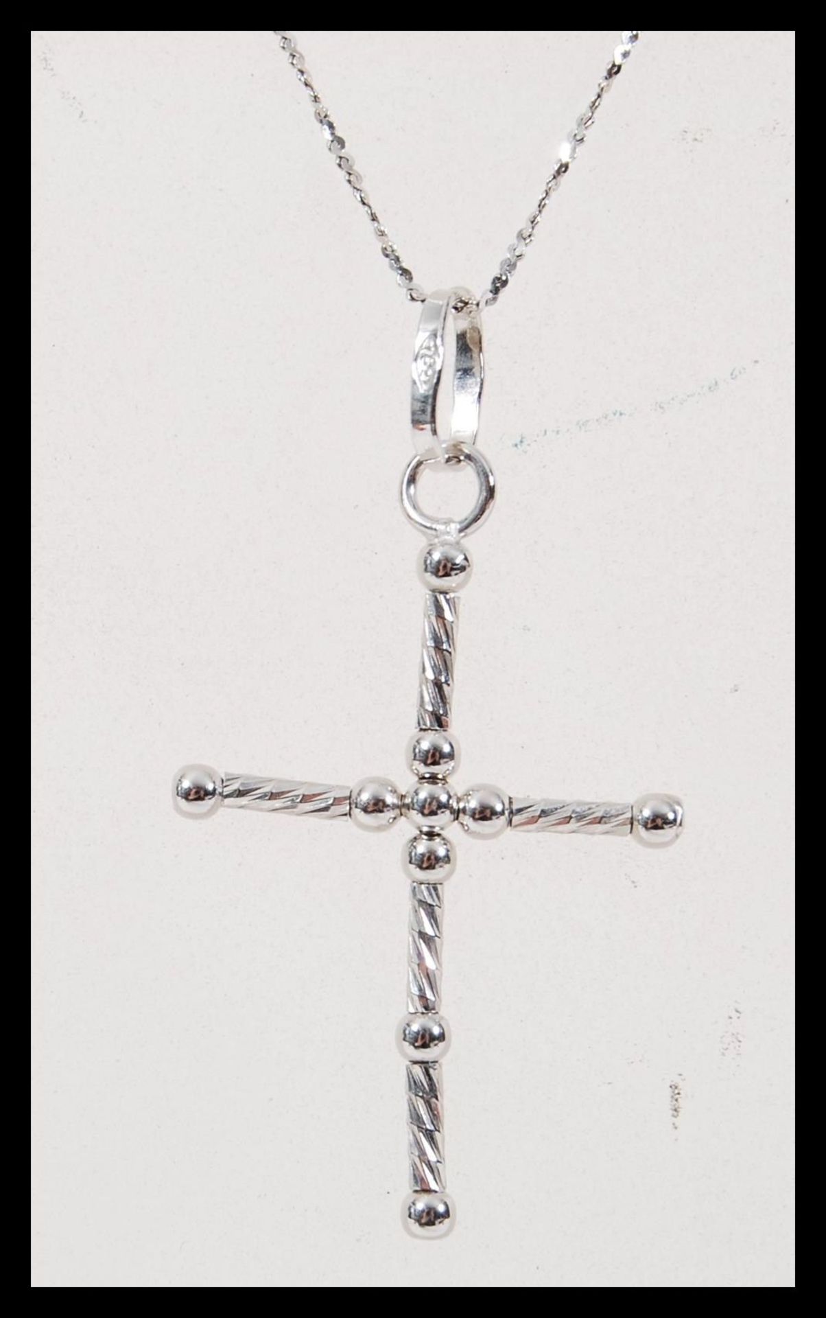 A stamped 750 white gold necklace having a crucifix pendant on a fine twisted chain. Chain