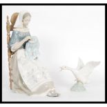 A Lladro porcelain figure depicting a woman doing embroidery seated in a chair along with a figurine