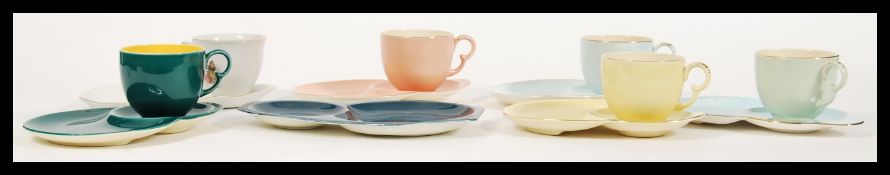 A small group of 20th Century tennis tea cups and saucers to include, four different coloured