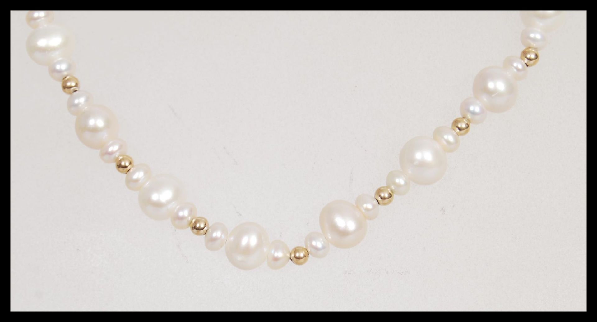 A 20th Century pearl necklace having repeating graduation design with a yellow metal pearl clasp.