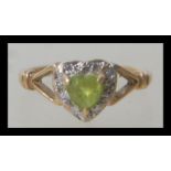 A hallmarked 9ct gold ring having a central heart shaped peridot stone with a halo of white