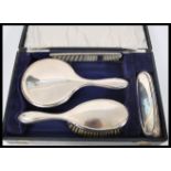 A vintage early 20th Century hallmarked silver brush set consisting of two brushes, mirror and