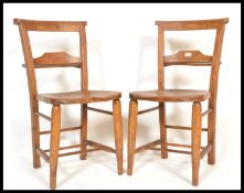 A pair of early 20th Century elm and beechwood chapel / school chairs with solid seats raised on